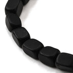 Närbild på kubformade frostade onyxpärlor i svart.