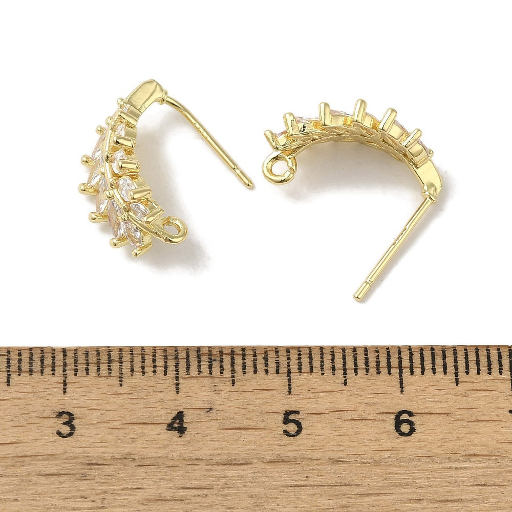 Guldpläterade öronkrokar med cubic zirconia mot en linjal.